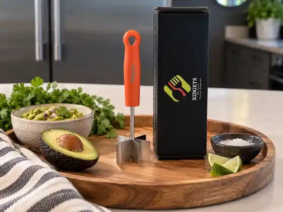 An orange-handled masher and a black Xidgets gift box on a wooden tray beside a bowl of guacamole